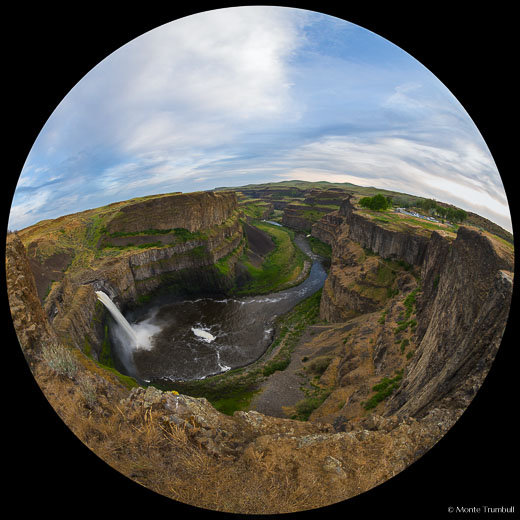A fish-eye view of the Palouse River gushing over Palouse Falls and flowing down a lush green valley into the distance on a beautiful spring day in Palouse Falls State Park in southeastern Washington.