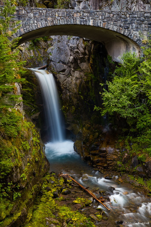 Van Trump Creek drops gracefully over the lower section of Christine Falls and flows underneath a rustic stone bridge in Mount Rainier National Park, Washington.